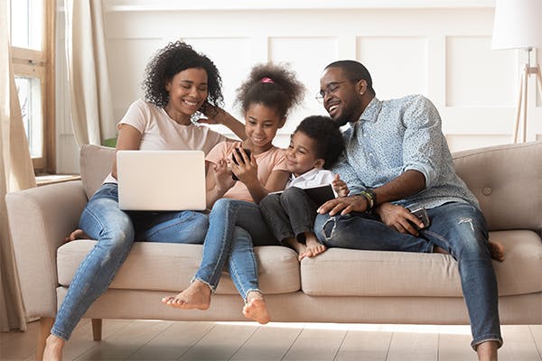 https://tower.10bestlifeinsurances.com/wp-content/uploads/2023/05/Happy-african-parents-and-kids-obsessed-addicted-to-gadgets-use-laptops-digital-tablet-phone-sit-on-sofa.jpg