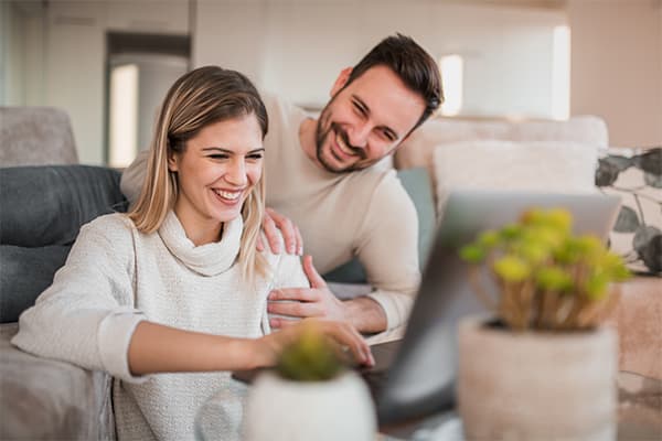 Happy-couple-using-laptop-in-their-living-room.